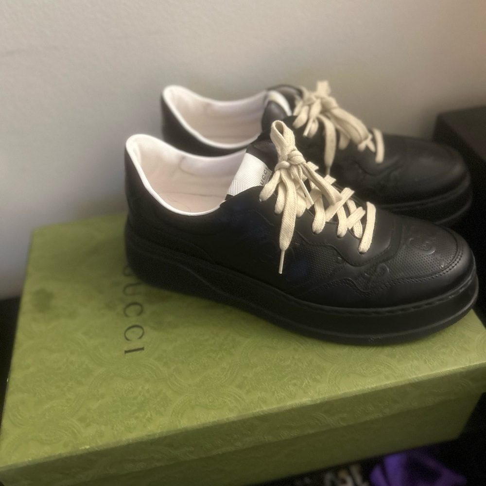 Men’s Gucci rimless glasses with gold arms and Gucci platform sneakers to match